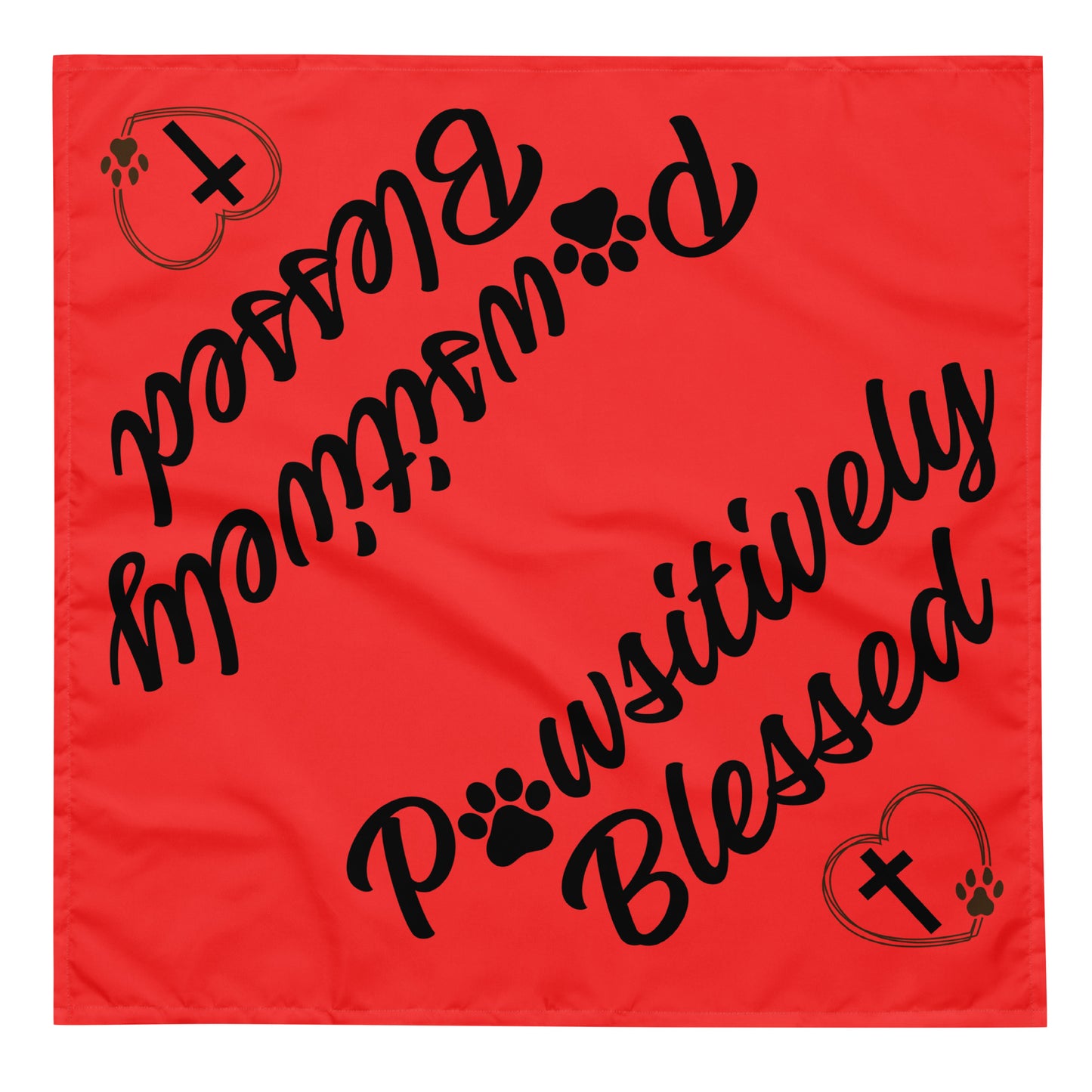 A square red bandana has, in black, the words Pawsitively Blessed and a heart, cross, and paw print on it twice, diagonally and opposite each other in black.