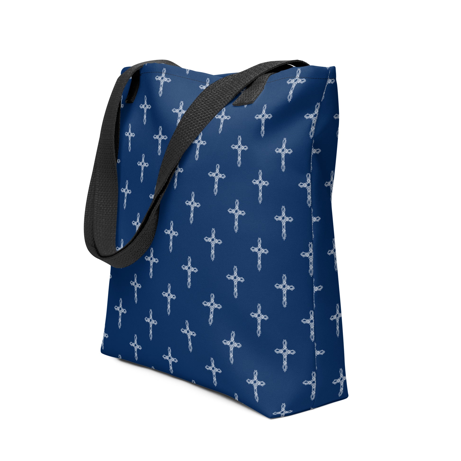 Navy blue tote bag or purse with white crosses on it and black handles flipped over the side.