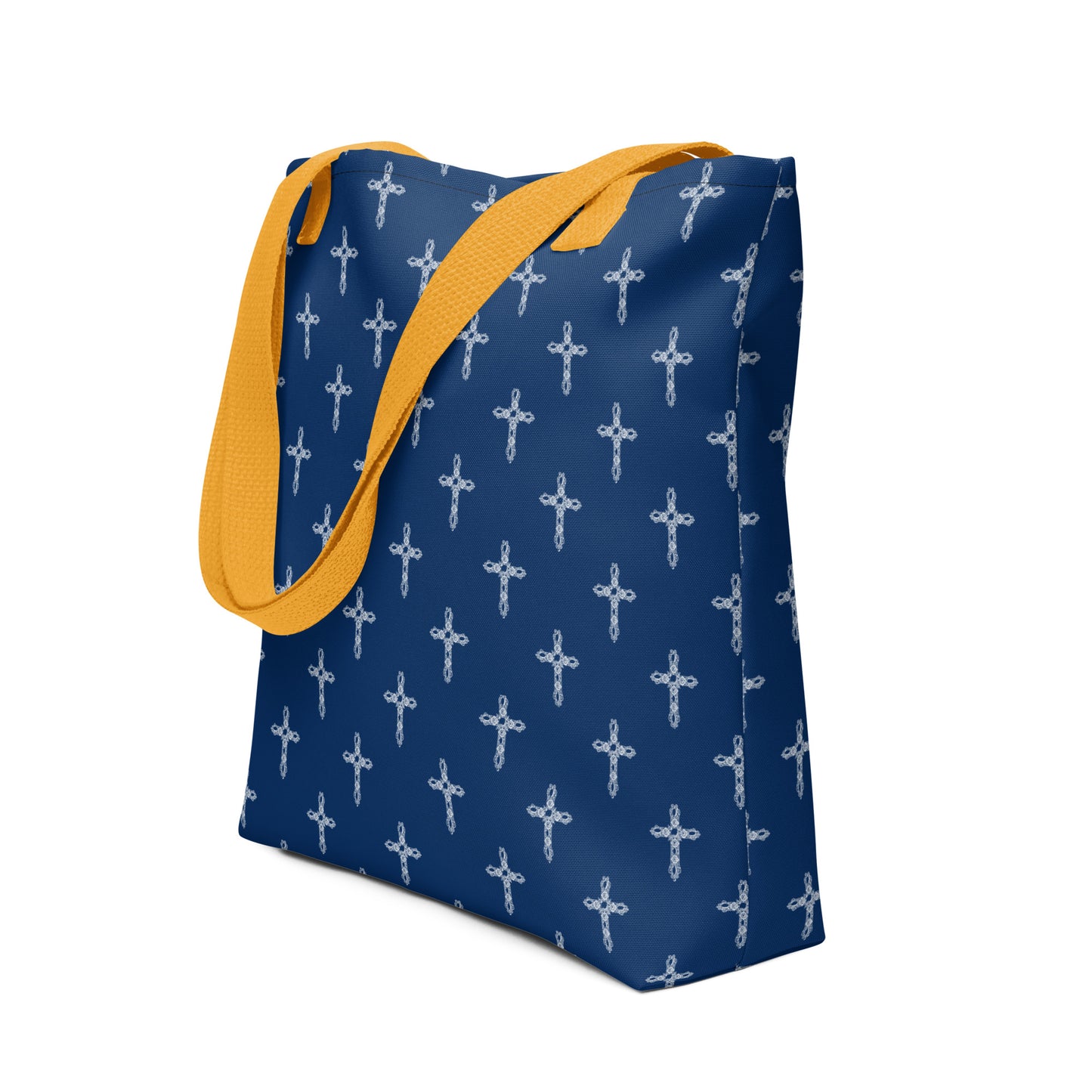 Navy blue tote bag or purse with white crosses on it and bright yellow handles flopped over onto one side of the bag.