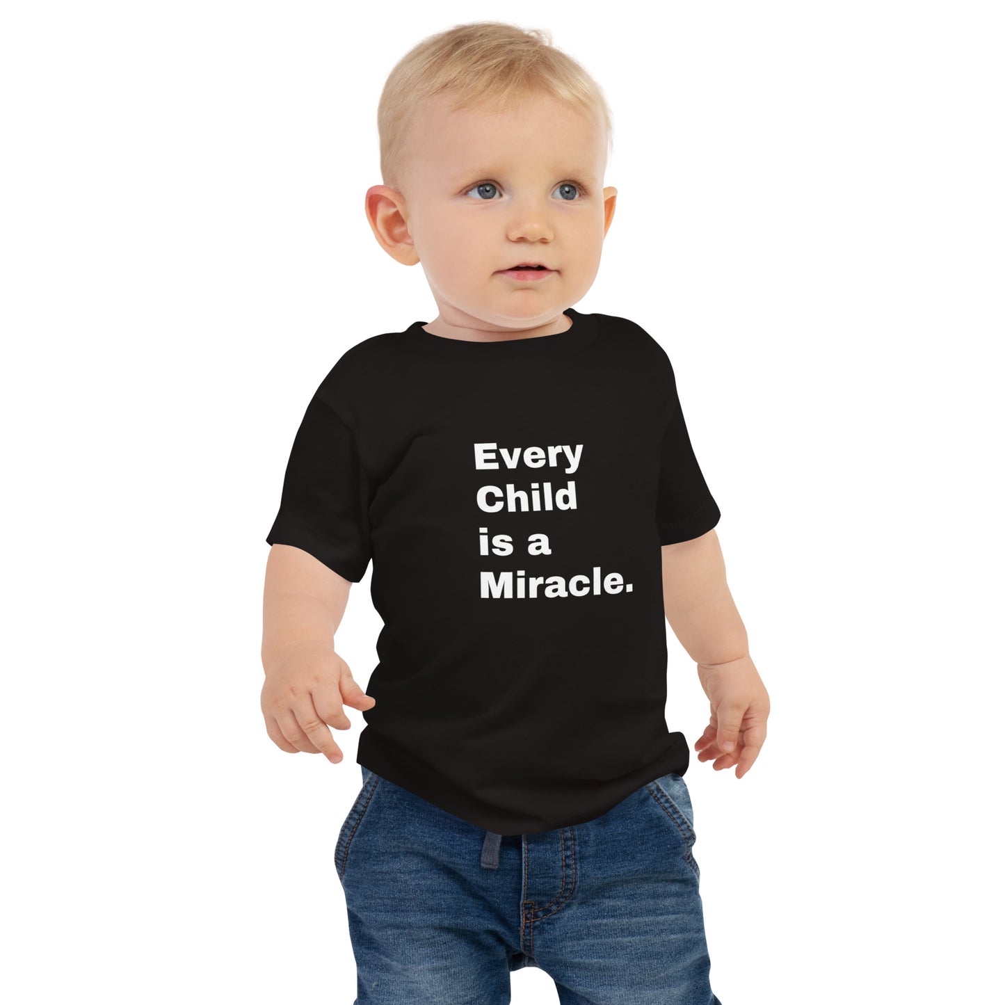 Toddler with blonde hair wearing bluejeans and a black t-shirt that says Every Child is a Miracle. in white text on the front.