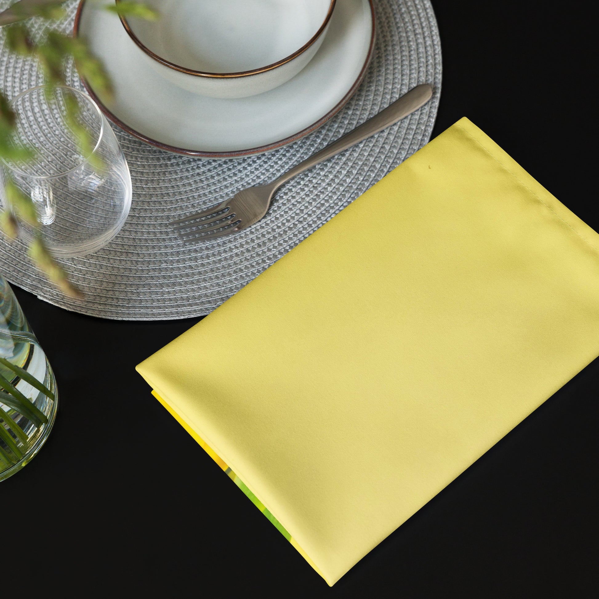 Yellow cloth napkin next to dinner place setting on a table.