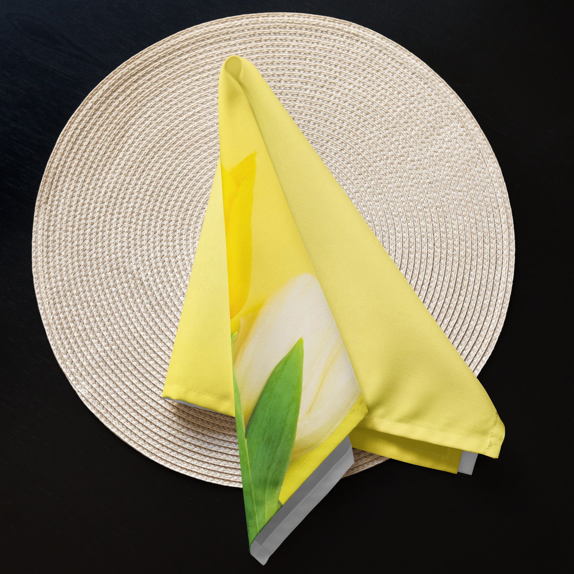 Yellow tulip cloth napkin folded creatively on round placemat.