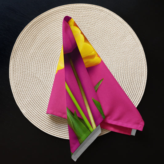 Pink fabric napkin with tulips on it folded to a point laying on a round woven placemat.