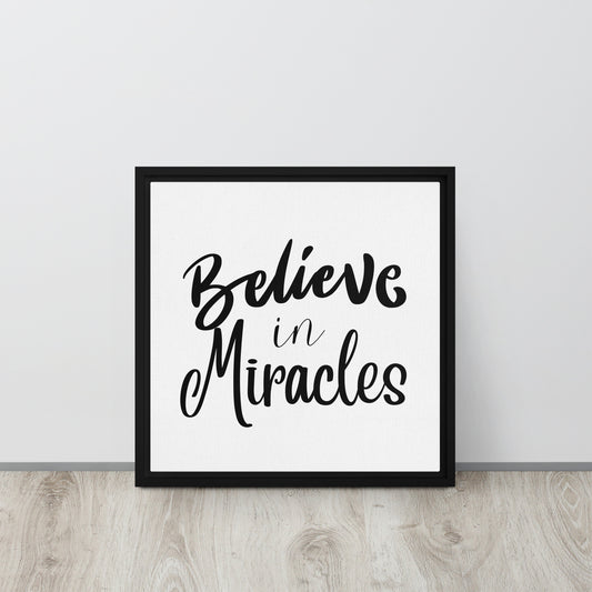 The words Believe in Miracles on white background in thick black  square frame leaned against white wall.