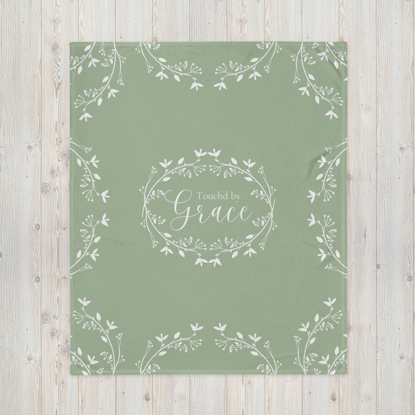 Sage green blanket with Touched by Grace in a white floral wreath in the center