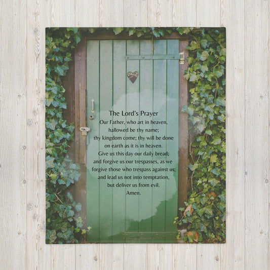 The Lord's Prayer Catholic version printed on a blanket. Background is a green door with ivy growing around it.