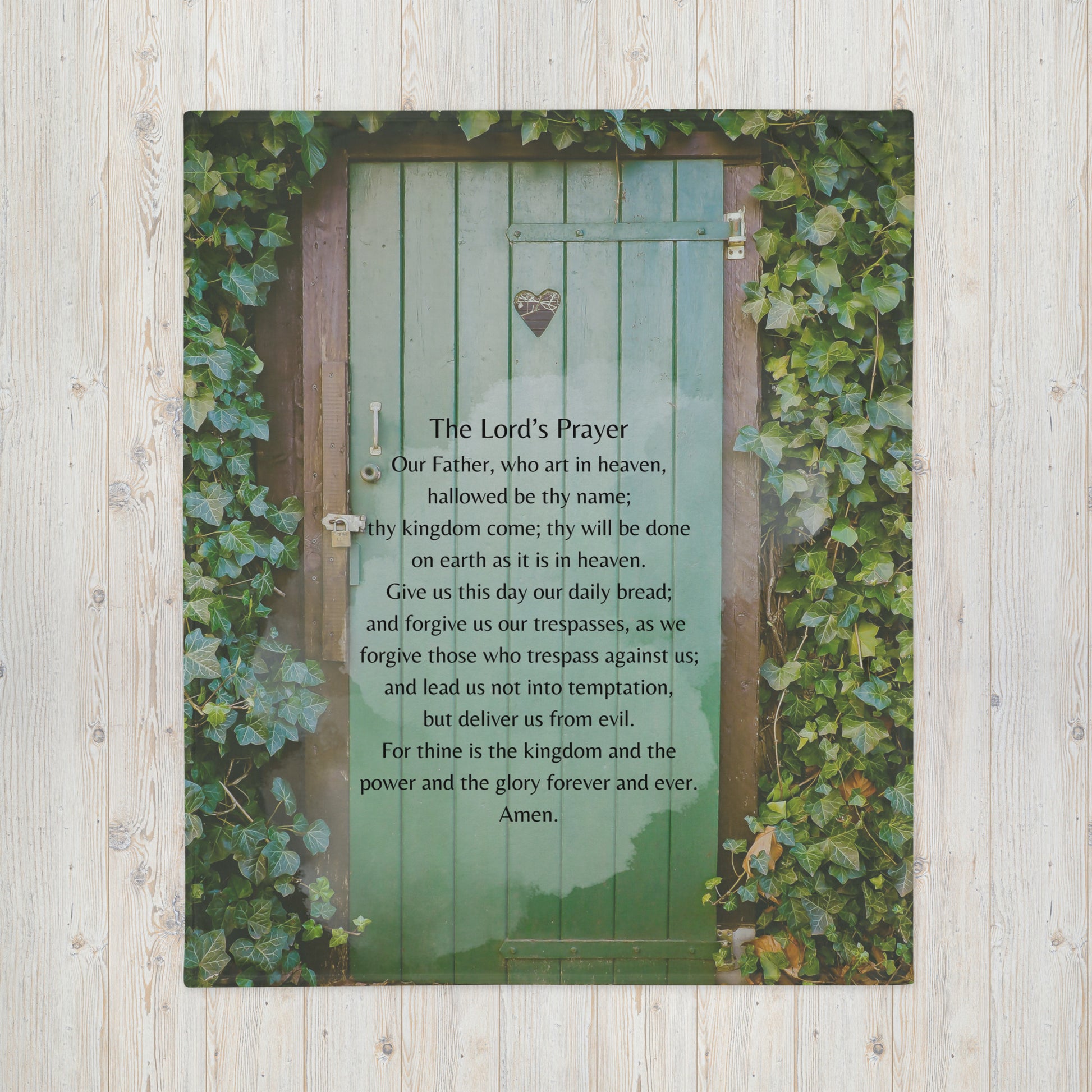 A throw blanket with The Lord's Prayer protestant version printed on a green door surrounded by ivy growing on the wall.