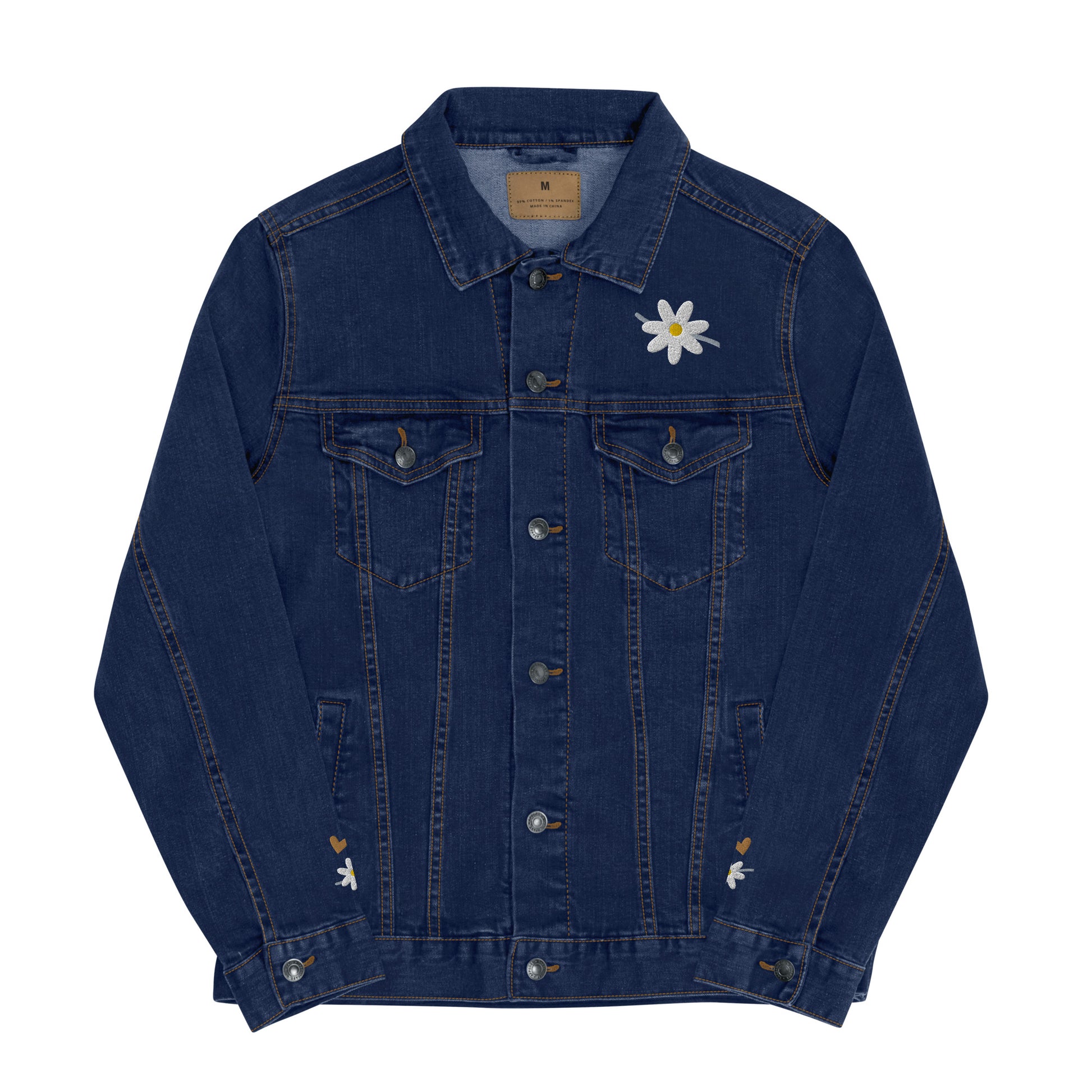 Front view of blue denim jean jacket with white daisy embroidered on the front left lapel area and partial view of daisies embroidered on wrist area above cuffs.