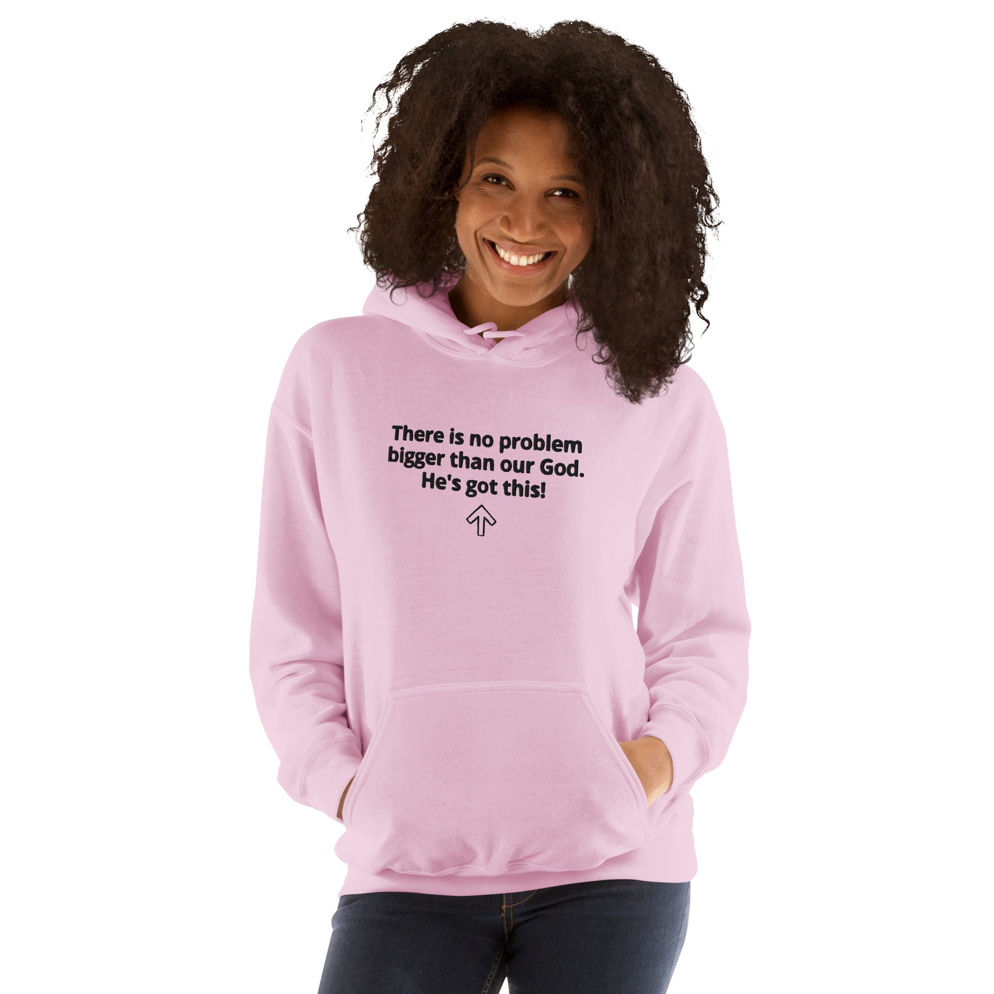 Smiling woman with curly dark hair standing  with her hands in the front pouch pocket of a pink hoodie that says "There is no problem bigger than our God. He's got this!" with an arrow that points up.