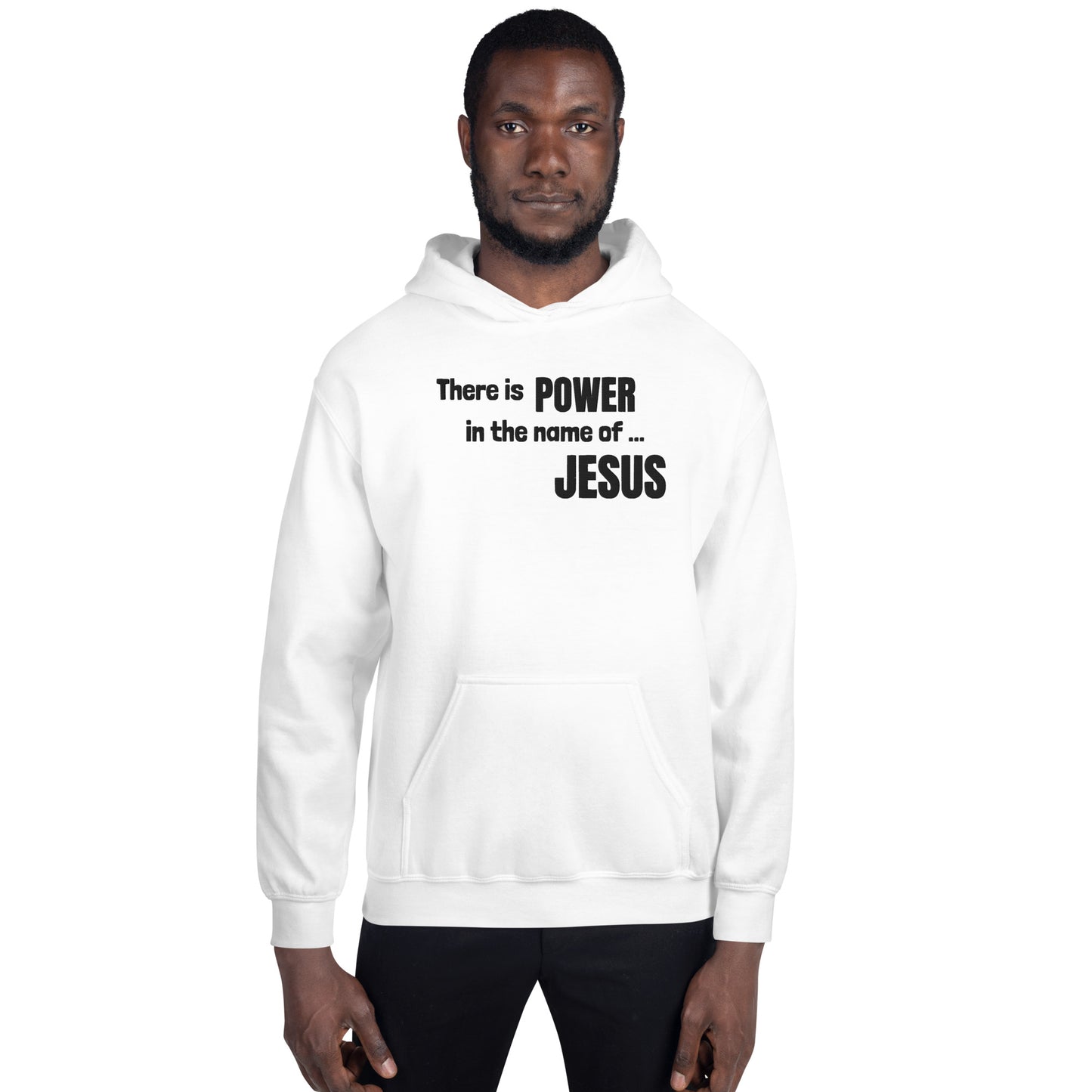 A three-quarter length photo of a man with very short dark hair and a short dark beard standing straight facing the camera wearing black pants and a white hooded sweatshirt or hoodie that is embroidered with the words:  There is POWER in the name of JESUS. 