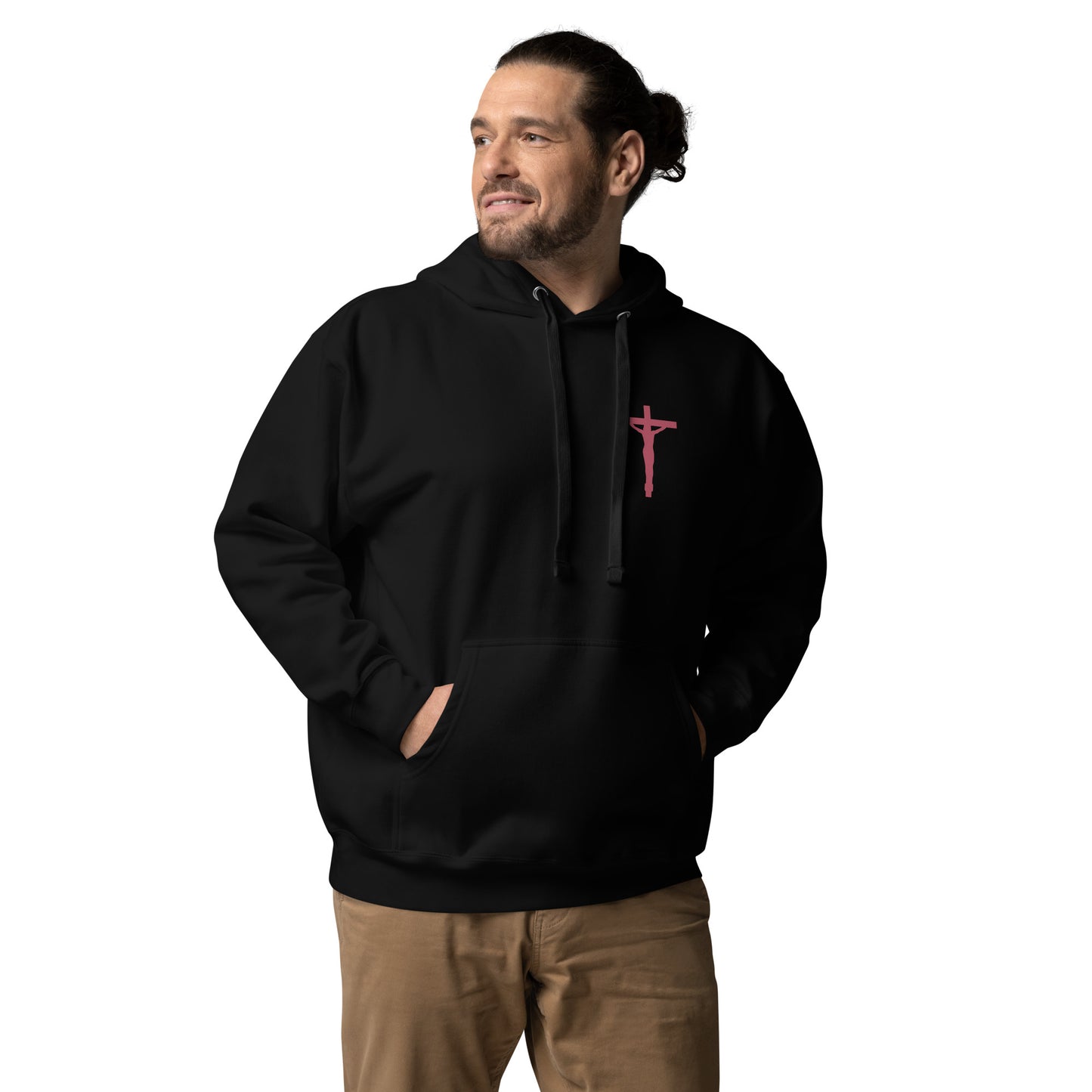 Man with hair in a bun and short beard and mustache is dressed in brown pants and a black hoodie with a red-tone crucifix on the front red chest spot, and his hands are in his front pouch pocket.