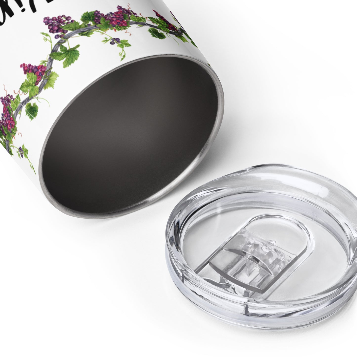 A plain white background on which lies a stainless steel wine cooler tipped on its side so you can see part of the way into it and you can only see the top of the wine tumbler and that it is bordered by grapevines with purple grapes and green leaves, and lying in front of it is the plastic lid for the tumbler.