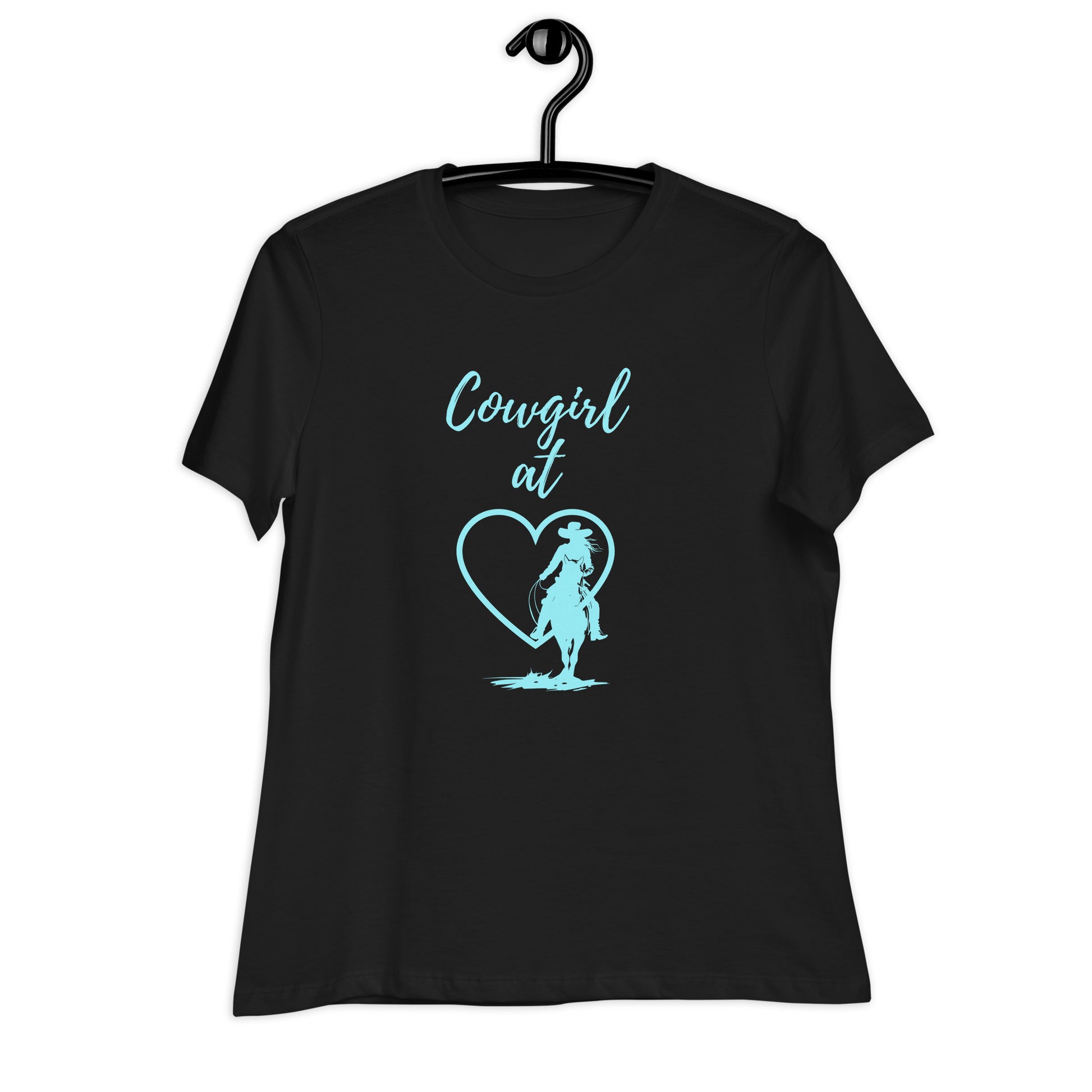 A black short-sleeved t-shirt on a black hanger on a white background and the t-shirt has an aqua design that says Cowgirl at and then a heart and a silhouette of a cowgirl on a horse.