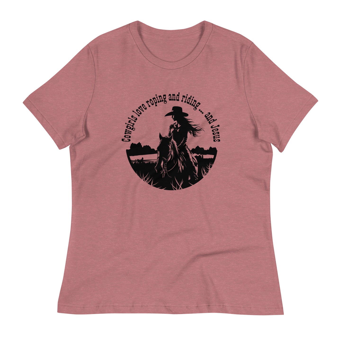 A dusty mauve round-necked short-sleeved t-shirt on a white background. The t-shirt features a circular design with the words Cowgirls love roping and riding ... and Jesus in the top half of the circle, arched kind of around it to make the circle shape and then the middle and lower part of the circle are made up of a girl riding a horse and she is wearing a cowboy hat.