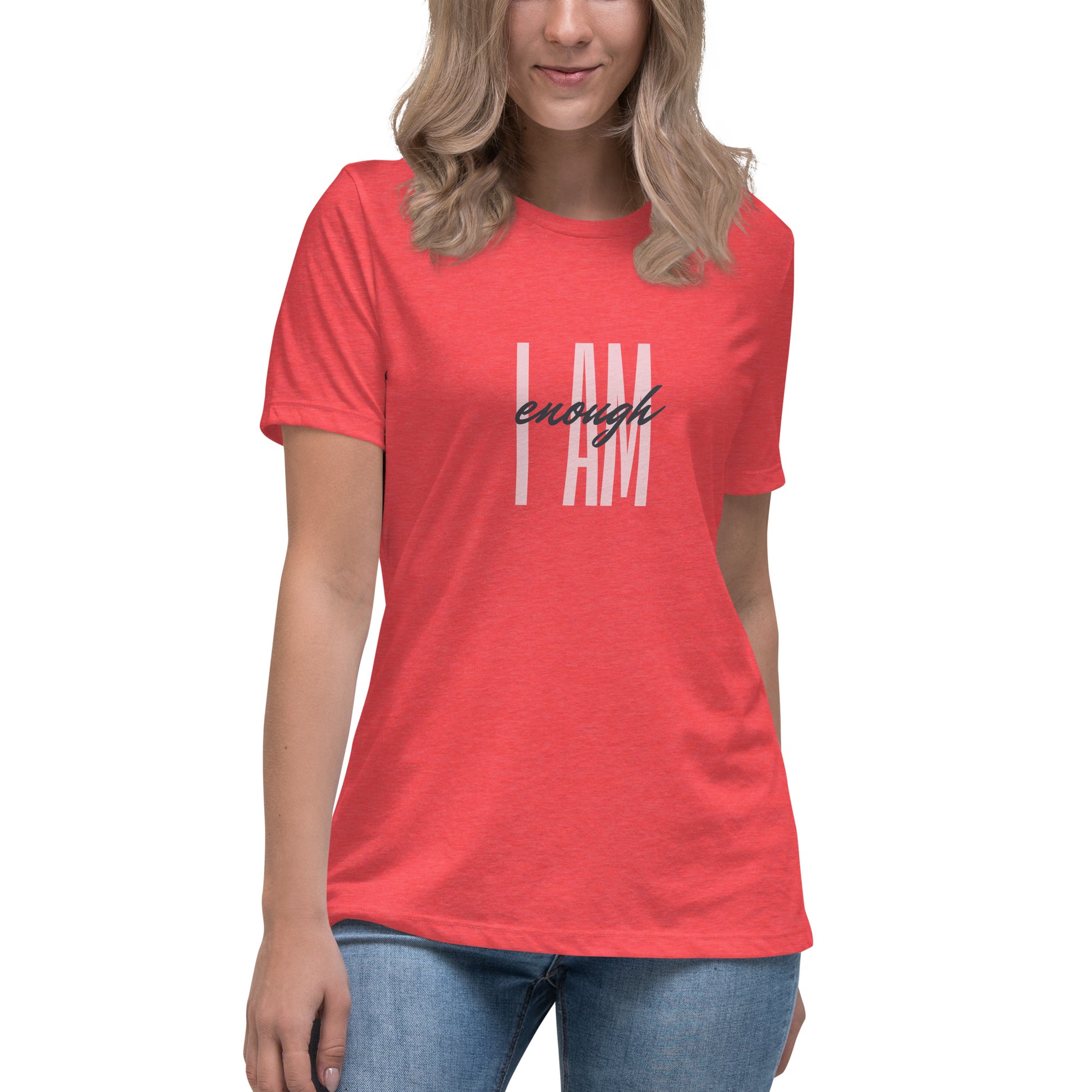 Middle section of a woman with long blond hair wearing medium color jeans and a peony color t-shirt that says I AM enough in two fonts across the middle.