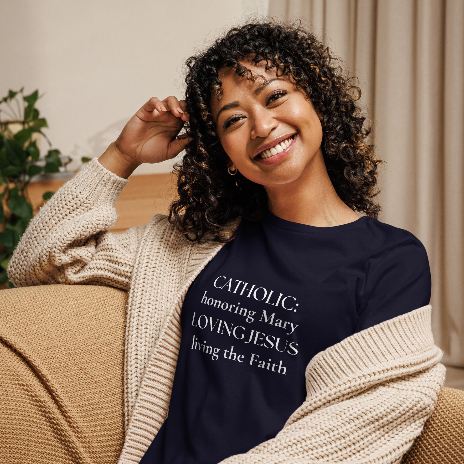 CATHOLIC: honoring Mary Loving Jesus living the Faith is loud and proud on the front of this navy t-shirt, worn by a smiling curly-haired woman.