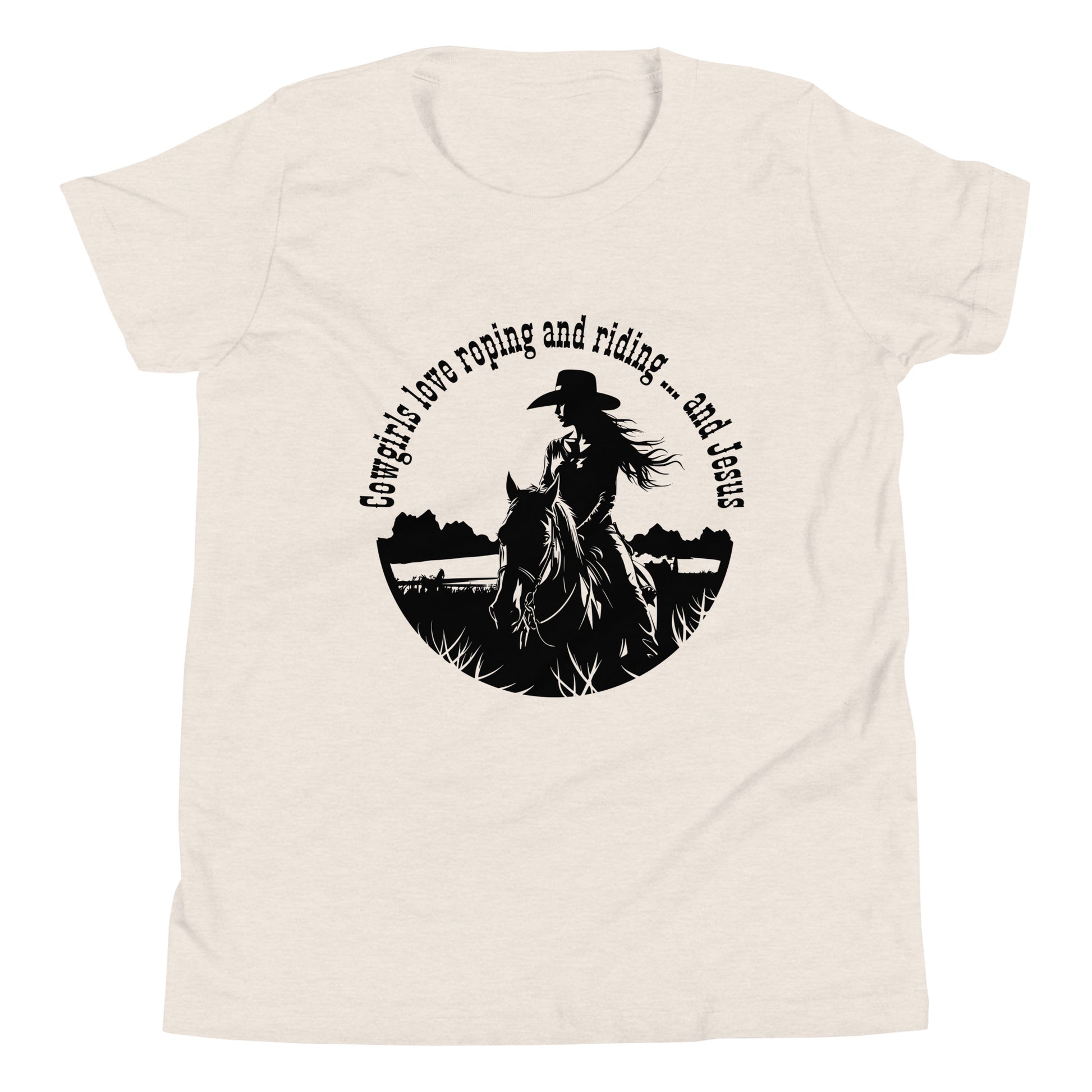 Off-white short-sleeved t-shirt with a black circular design on the front features a cowgirl on horseback with long flowing hair and a cowboy hat on the girl and the words:  Cowgirls love roping and riding ... and Jesus.